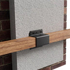 Metal bracket attached to a wooden beam against a brick wall.