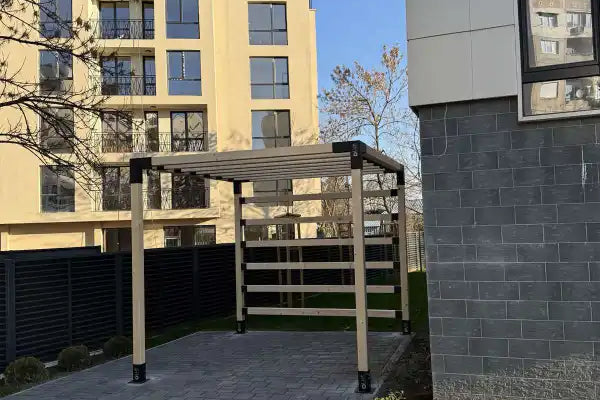 Paved area with a wooden pergola in front of residential buildings